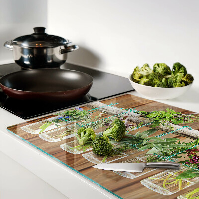 Glass chopping board Herbs in jars on a wooden background