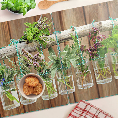 Glass chopping board Herbs in jars on a wooden background