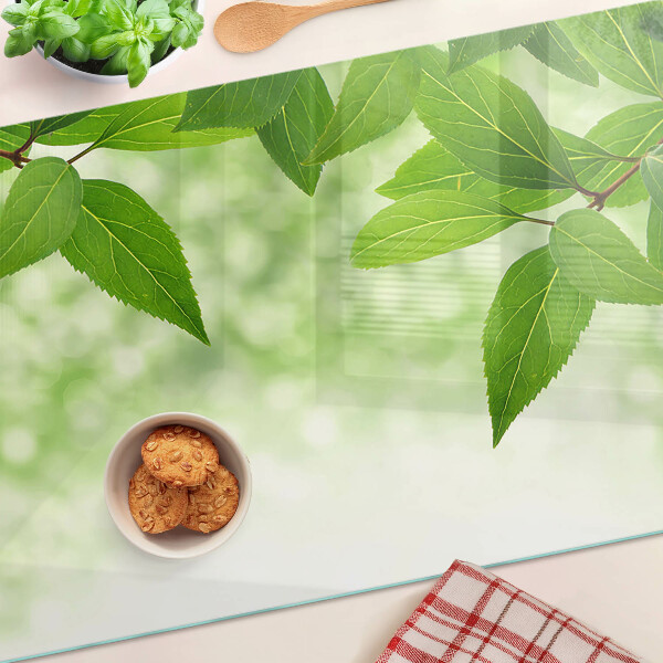Chopping board glass Leaves against a background of blurred greenery