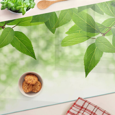 Chopping board glass Leaves against a background of blurred greenery