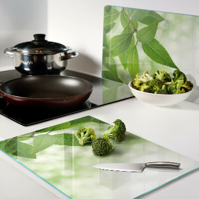 Chopping board glass Leaves against a background of blurred greenery