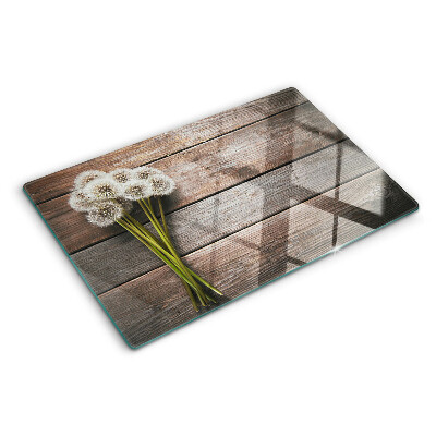 Glass chopping board Dandelion flowers on a wooden background