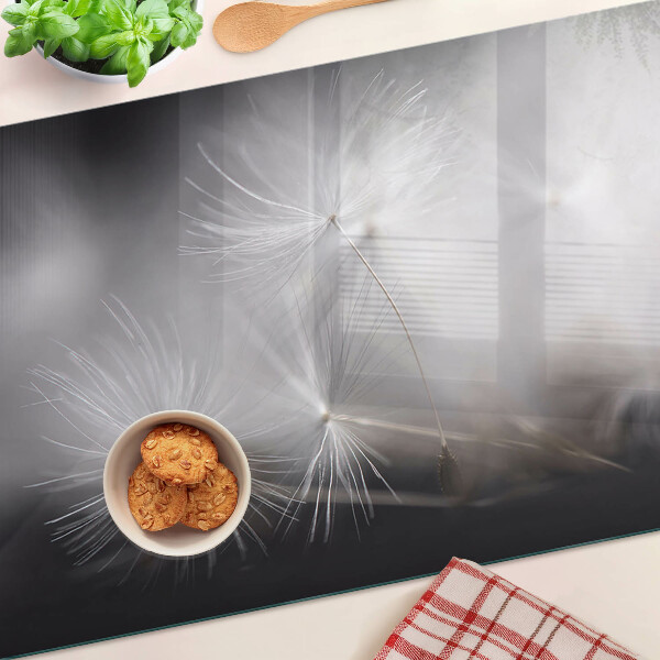 Glass chopping board Fluffy dandelions against the window background
