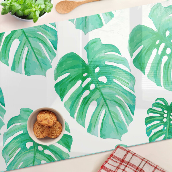 Glass cutting board Monstera leaves on a white background