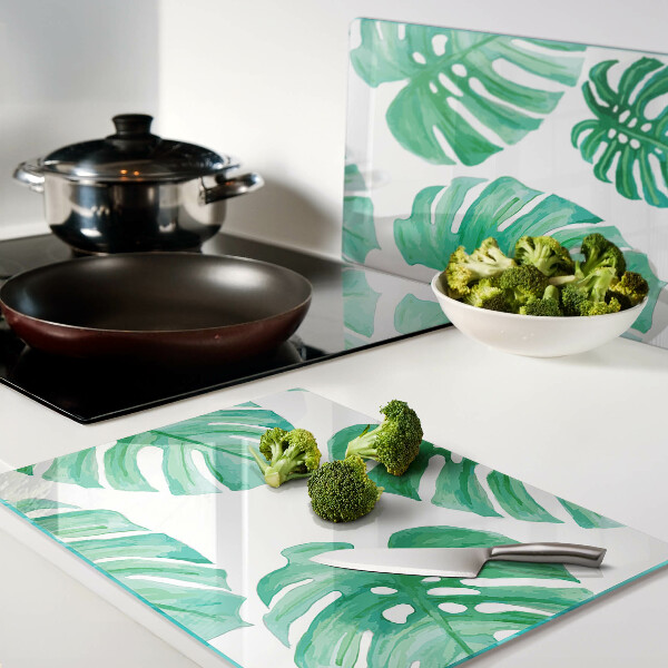 Glass cutting board Monstera leaves on a white background