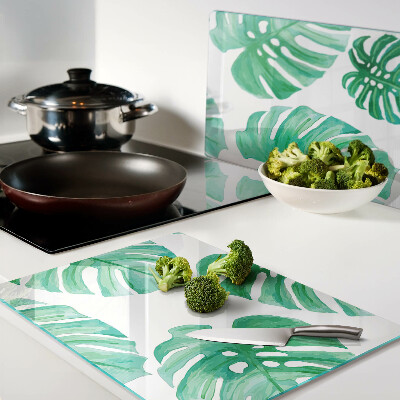Glass cutting board Monstera leaves on a white background