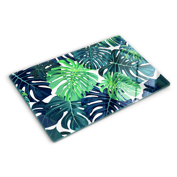 Glass chopping board Monstera leaves on a tropical background