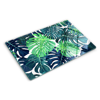 Glass chopping board Monstera leaves on a tropical background