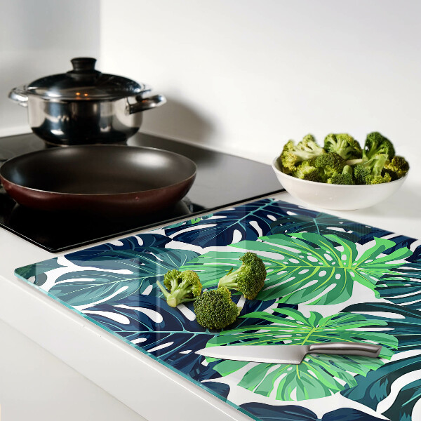 Glass chopping board Monstera leaves on a tropical background