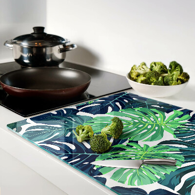 Glass chopping board Monstera leaves on a tropical background