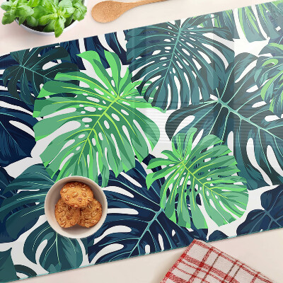 Glass chopping board Monstera leaves on a tropical background