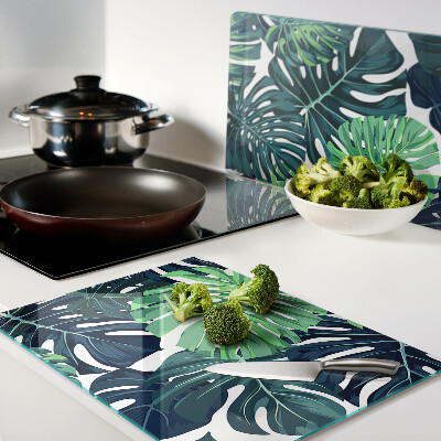 Glass chopping board Monstera leaves on a tropical background