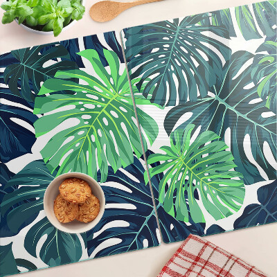 Glass chopping board Monstera leaves on a tropical background