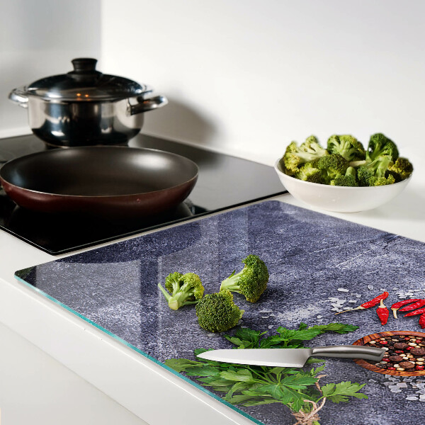 Glass chopping board Herbs and spices on a stone background