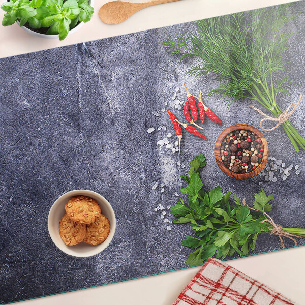 Glass chopping board Herbs and spices on a stone background