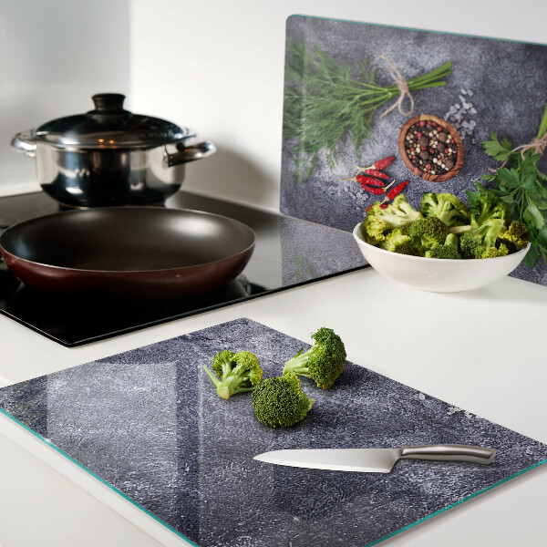 Glass chopping board Herbs and spices on a stone background