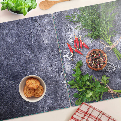 Glass chopping board Herbs and spices on a stone background