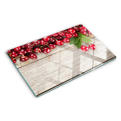 Glass cutting board Cherries on a wooden background