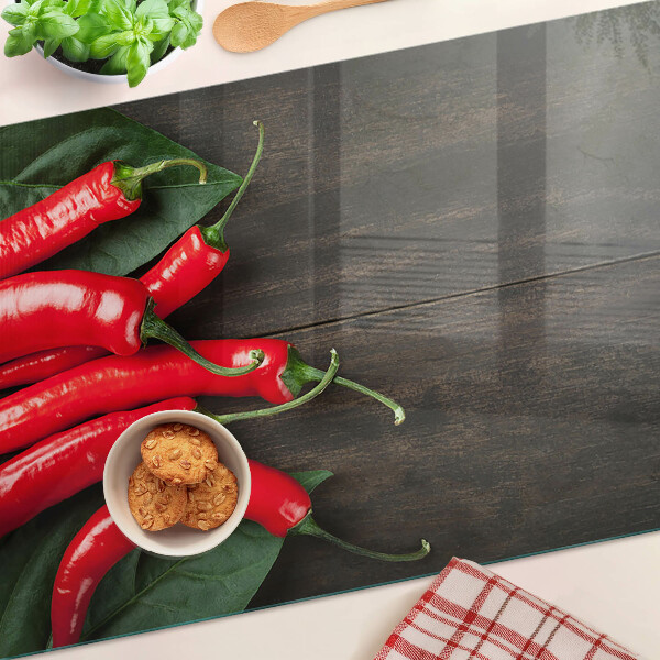 Glass cutting board Chili peppers on a wooden background