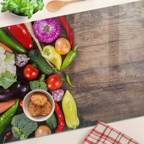 Glass cutting board Vegetables on a wooden background