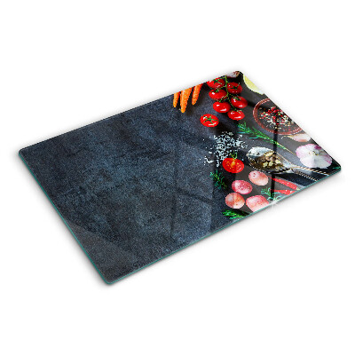 Glass cutting board Vegetables and spices on a dark background