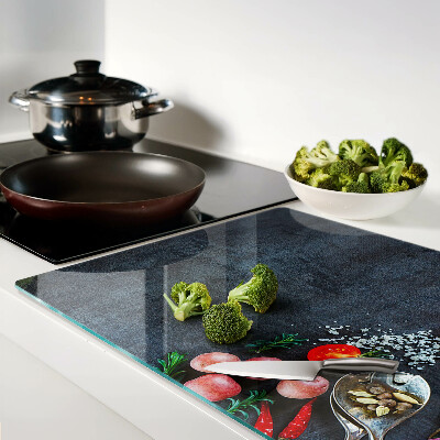Glass cutting board Vegetables and spices on a dark background