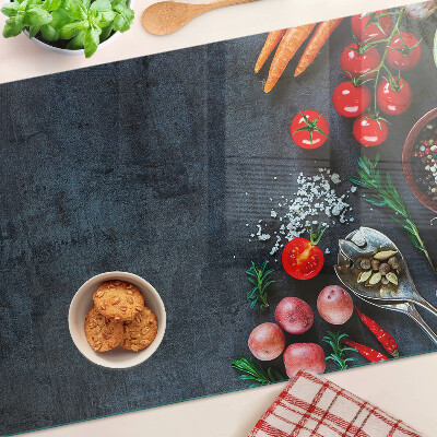 Glass cutting board Vegetables and spices on a dark background