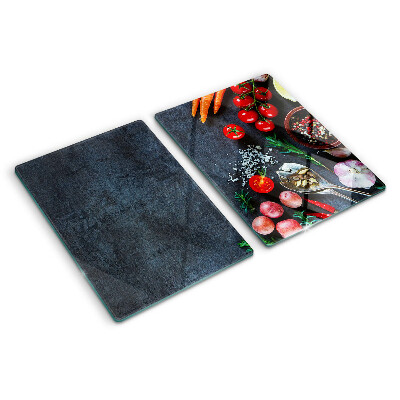 Glass cutting board Vegetables and spices on a dark background