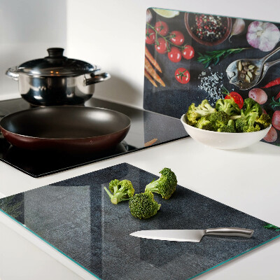 Glass cutting board Vegetables and spices on a dark background