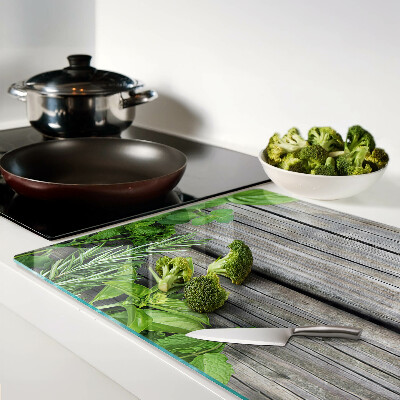 Chopping board glass Green herbs on a wooden background